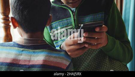 Gros plan de deux garçons d'Asie du Sud, l'un d'eux avec un téléphone portable Banque D'Images