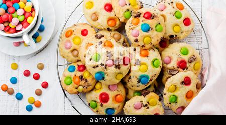 Biscuits pour enfants avec bonbons au chocolat colorés en glaçage au sucre sur fond de bois blanc.Mise au point sélective.Vue de dessus.Placer pour le texte. Banque D'Images