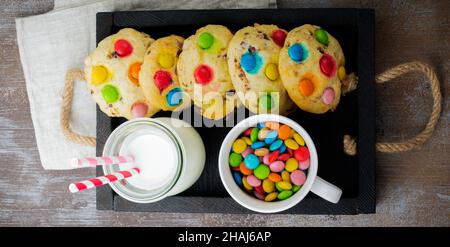 Biscuits pour enfants avec bonbons au chocolat colorés en glaçage au sucre sur fond de bois brun.Mise au point sélective.Vue de dessus.Placer pour le texte. Banque D'Images