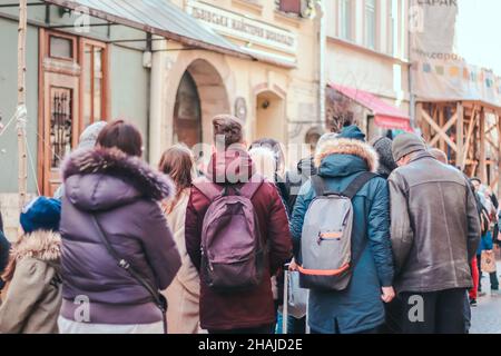 Une foule anonyme de personnes se trouve dans la file d'attente d'un magasin, d'un centre commercial pendant une pandémie, en descendant une rue de la ville.Les touristes se rendent en Europe.Vue arrière Banque D'Images