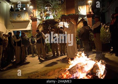 Malaga, Espagne.13th décembre 2021.Un prêtre est vu bénir un feu de joie lors de la célébration de la procession de la Vierge de 'Divina Pastora'.À la veille de la fête de Sainte-Lucie dans le petit village de Casarabonela, chaque nuit du 12 décembre pendant la saison de Noël, les villageois prennent part à la célébration antique de 'Los Rondeles' portant des paniers de wckers en feu (également connu sous le nom de 'rondeles') trempés dans l'huile.Le long des rues, la Vierge de 'Los Rondeles' est honorée par les dévotés dans un rituel de lumière et de feu comme action de grâce pour la récolte obtenue.Crédit : SOPA Images Limited/Alamy Live News Banque D'Images