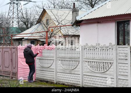 Mayorske, Ukraine.11th décembre 2021.Une femme a vu peindre la clôture de sa maison dans le village de Mayorske.Mayorske est situé juste près du point de contrôle de l'Ukraine dans la région de Donetsk sur la ligne de front.Le travail du point de contrôle 'Mayorske' est toujours suspendu.Les tensions sont fortes lorsque les forces militaires russes se rassemblent près de la frontière ukrainienne.Crédit : SOPA Images Limited/Alamy Live News Banque D'Images