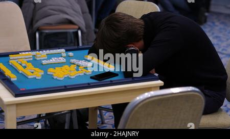 Un jeune homme qui est très fatigué après avoir joué à mahjong pendant longtemps.Le jeune homme s'est couché pour se reposer sur la table de mahjong.Jeu de société asiatique traditionnel Banque D'Images