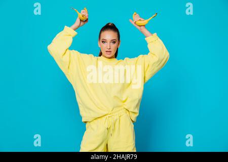 femme en vêtements jaunes avec fruit banane sur fond bleu Banque D'Images