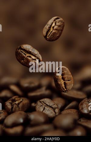 Gros plan de grains de café tombant dans une pile de haricots sur fond sombre Banque D'Images