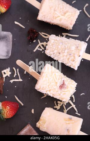 Des popsicles faits maison aux saveurs différentes sur la table noire avec des fraises Banque D'Images