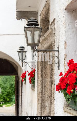 Lampe de rue et fleurs rouges à l'entrée du monastère Hoeglwoerth, Bavière, Allemagne Banque D'Images