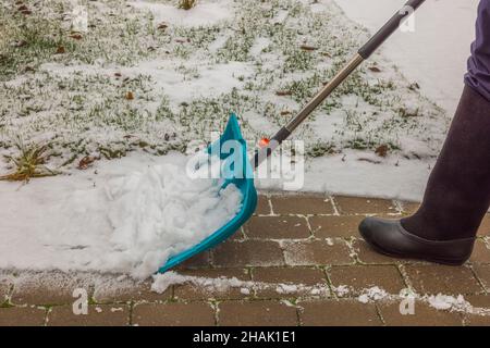 Vue d'un homme dans des bottes en feutre qui pelent de la neige sur des dalles.Suède. Banque D'Images