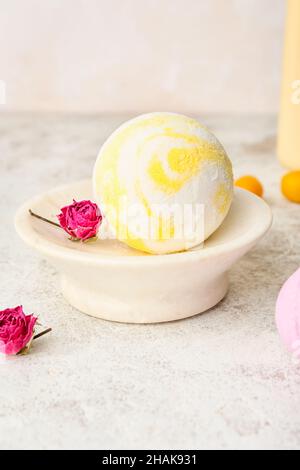 Bol avec bombe de bain et fleurs de rose séchées sur fond clair, gros plan Banque D'Images