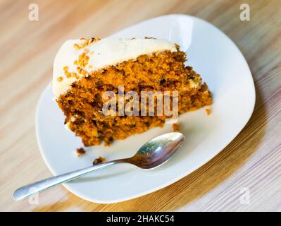 Tranche de gâteau de carotte douce avec glaçage au fromage à la crème sur une table en bois. Banque D'Images