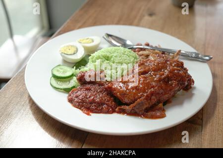 Riz à la noix de coco Nasi Lemak avec poulet frit épicé, œuf dur, curry, arachides, anchois et concombres.Prêt à manger. Banque D'Images