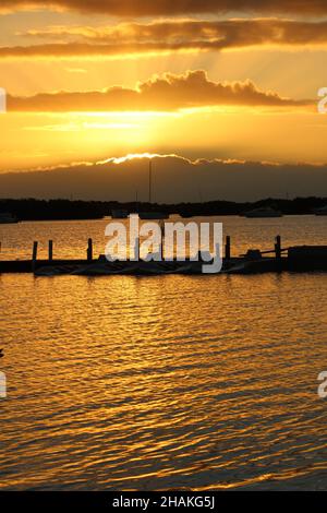 Des faisceaux de lumière éclairent à travers les nuages au lever du soleil et réfléchissent au large de l'eau à Key West Florida. Banque D'Images