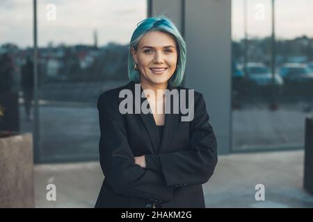 Portrait d'une femme d'affaires avec des cheveux bleus dehors, posant avec les bras pliés.Personne d'affaires réussie.Portrait de femme d'affaires. Banque D'Images