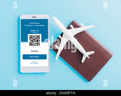 Modèle d'avion, passeport et carte d'immunité sont arrangés application sur smartphone sur fond bleu, Travel concept pendant Covid-19 pandémie numérique Banque D'Images