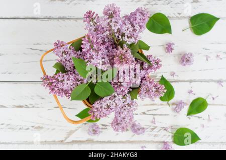 vue de dessus du bouquet de printemps de lilas violets dans un panier de fleurs sur fond de bois blanc. composition de printemps pour créer une bonne humeur Banque D'Images