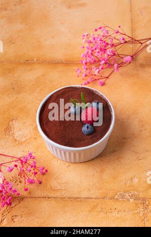 dessert tiramisu avec baies sur fond brun et fleurs roses Banque D'Images