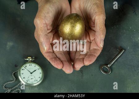 Main tenant économiser de l'argent dans l'oeuf d'or et le temps et la clé de maison, concept d'investissement financier d'affaires Banque D'Images