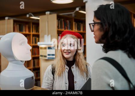 Étudiants utilisant l'assistant vocal dans la bibliothèque Banque D'Images