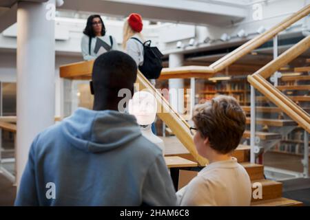 Étudiants utilisant l'assistant vocal dans la bibliothèque Banque D'Images