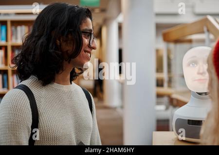 Étudiants utilisant l'assistant vocal dans la bibliothèque Banque D'Images