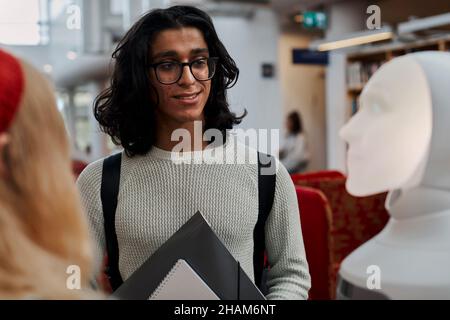 Étudiants utilisant l'assistant vocal dans la bibliothèque Banque D'Images