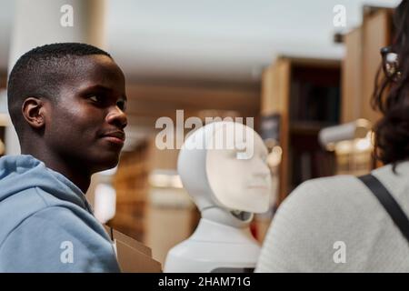 Étudiants utilisant l'assistant vocal dans la bibliothèque Banque D'Images