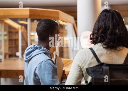 Étudiants utilisant l'assistant vocal dans la bibliothèque Banque D'Images