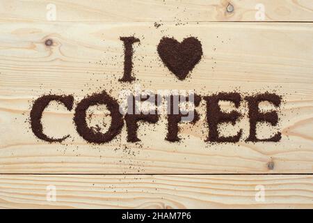Le texte « J'aime le café » écrit avec du vrai café moulu sur une surface en bois de pin Banque D'Images