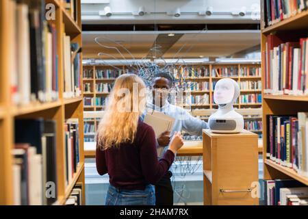 Étudiants utilisant l'assistant vocal dans la bibliothèque Banque D'Images