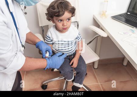 Le pédiatre prélève un échantillon de sang sur un enfant pour vérifier les niveaux de glucose. Banque D'Images