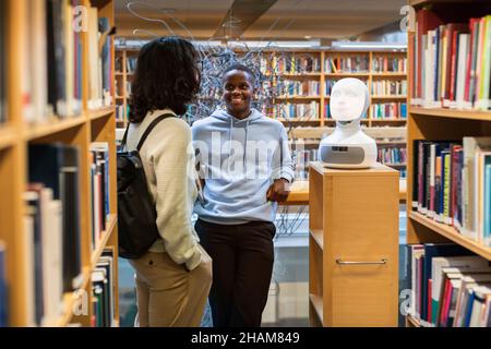 Étudiants utilisant l'assistant vocal dans la bibliothèque Banque D'Images