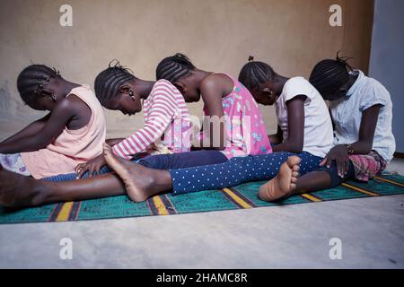 Groupe d'enfants africains à vue latérale assis sur le sol ensemble, la tête vers le bas sur le dos.Traditions , style de vie et diversité culturelle concept AMO Banque D'Images