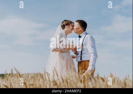 Mariée et marié tenant des verres de champagne de mariage sur le fond du champ de blé.Couple de mariage heureux dans champ de blé.Belle mariée en blanc Banque D'Images