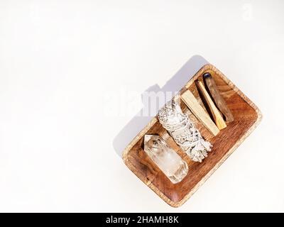 Articles pour le nettoyage spirituel - ensemble de sauge, bâtonnets d'encens palo santo et cristal de quartz sur plateau en bois sur fond blanc.Vue de dessus.Copier l'espace Banque D'Images