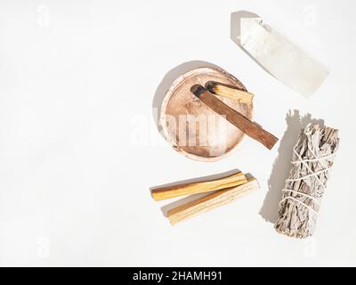 Articles pour le nettoyage spirituel - ensemble de sauge, bâtonnets d'encens palo santo et cristal de quartz sur fond blanc.Vue de dessus.Copier l'espace Banque D'Images