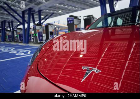 14 décembre 2021, Rhénanie-du-Nord-Westphalie, Kamen : les cellules solaires du toit de l'installation se reflètent dans le capot d'une voiture électrique Tesla se tenant à une station de charge du Kamener Kreuz avant l'ouverture du plus grand parc à chargement rapide de voitures électroniques de la société énergétique EnBW à ce jour.Il y a 52 points de charge rapide sur le site.EnBW déclare qu'elle exploite le plus grand réseau public de chargement rapide d'Allemagne, avec plus de 650 de ses propres sites à travers le pays.D'ici 2025, la société prévoit d'exploiter 2500 sites de chargement rapide.EnBW prévoit d'investir environ 100 millions d'euros par an dans ce projet.Photo: Bernd th Banque D'Images