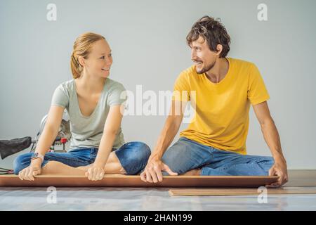 Couple marié installant un nouveau parquet stratifié en bois sur un plancher de film chaud.Système de chauffage au sol infrarouge sous sol stratifié Banque D'Images