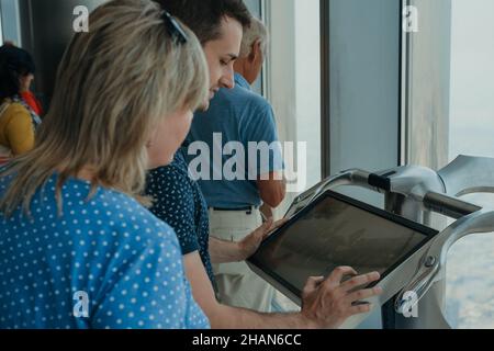 Jeune homme touriste adulte utilisant un télescope électronique numérique du Burj Khalifa sur la terrasse d'observation Banque D'Images