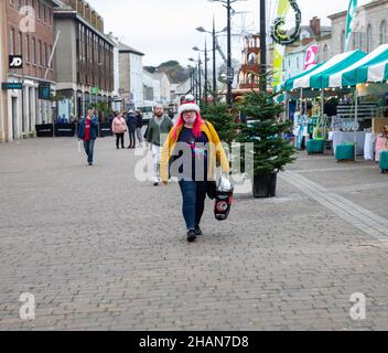 Truro, Royaume-Uni, 14th décembre 2021, Une dame vêtue de façon festive traverse Lemon Quay le jour du marché à Truro, en Cornouailles.Elle portait un chapeau de père Noël et un pull de Noël.Le temps a été couvert mais doux pour la période de l'année à 12C et une douce brise.Credit: Keith Larby/Alamy Live News Banque D'Images