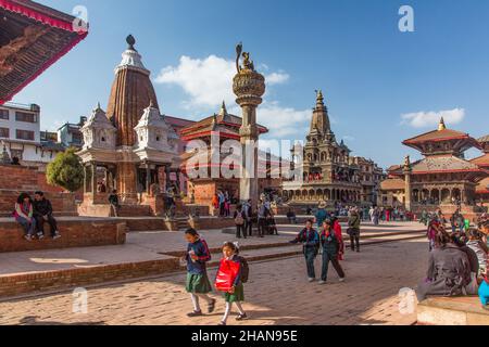 Visiteurs aux temples de Durbar Square, Patan, Népal.De gauche à droite : temple de Narasimha, statue du roi Yoganarendra Malla, temple Krishna Mandir, statue de Hanuman Banque D'Images