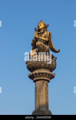 Les pigeons perches sur la statue en laiton de Garuda sur une colonne en pierre de la place Durbar, Patan, Népal. Banque D'Images
