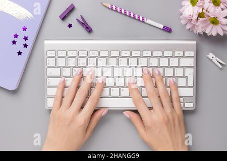 Femme utilisant un clavier sur un bureau gris avec ordinateur portable, papeterie Banque D'Images