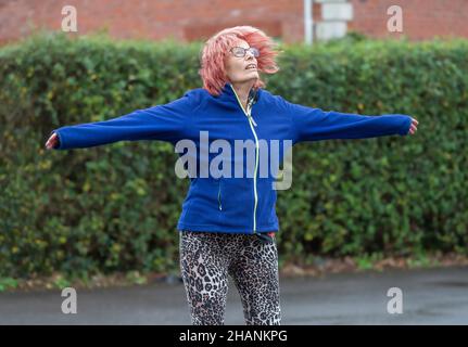 Femme âgée de 80s ans qui fait de l'exercice à l'extérieur en faisant des sauts d'étoiles en hiver.Vieille dame gardant un mode de vie actif et sain. Banque D'Images