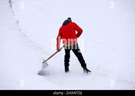 Homme avec une pelle élimine la neige à l'extérieur.Employé pendant le déneigement en ville d'hiver, nettoyage de la rue Banque D'Images