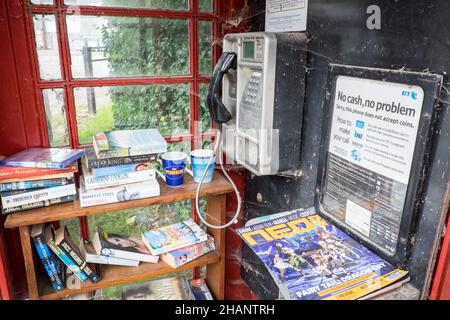 Intérieur,intérieur,iconique,rouge,BT,téléphone,boîte,boîte,téléphone,kiosque,mise,à,nouveau,usage,conversion,converti,en,recyclé,nouvelle,fonction,usage,a,mini,livre,bibliothèque,échange, étagères,dans,village,de,Stoughton,Ouest,Sussex,Ouest,Sussex,Angleterre,Anglais,GB,Grande-Bretagne,Royaume-Uni,Royaume-Uni,Royaume-Uni Banque D'Images