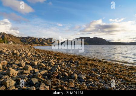 La plage rocheuse couverte d'algues à Lower Diabaig, Wester Ross, en début de soirée.Vue sur la jetée (Sgeir Ghlas), le Loch Diabaig et Rhuba na h-Airde Banque D'Images