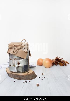 Harengs marinés, poivre et épices dans un pot sur la table, fond clair, photo verticale Banque D'Images