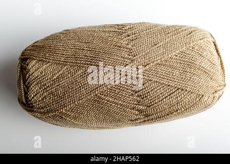 Un fil de laine brun clair à coudre ou à broder isolé sur une table blanche, vue latérale des matières textiles Banque D'Images