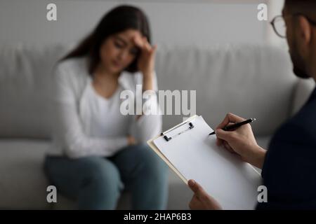 La femme du Moyen-Orient déprimé consultant psychologue au bureau médical, se concentrer sur l'écriture psychiatre dans le presse-papiers Banque D'Images