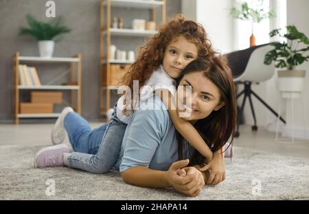 Portrait d'une mère et de sa petite fille couchée ensemble sur un tapis dans le salon. Banque D'Images